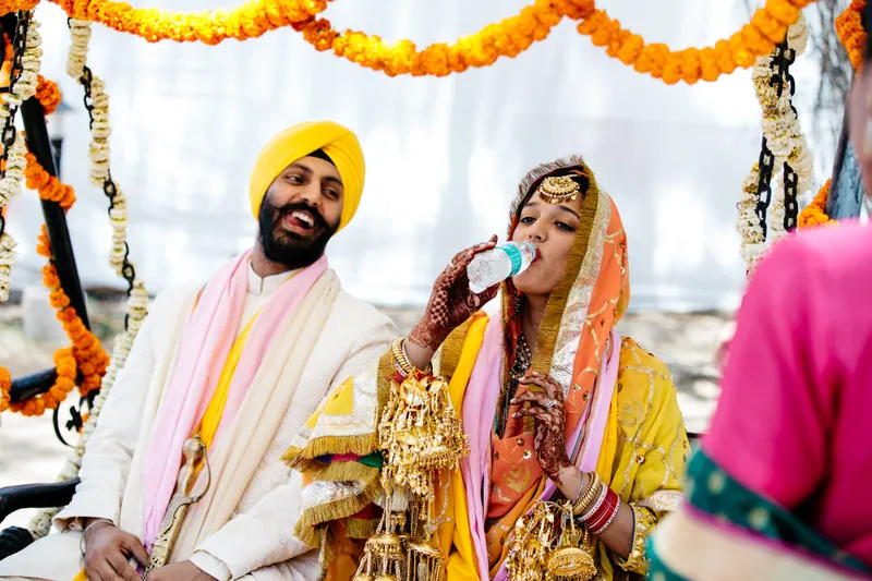 Bride drinking water, groom laughing